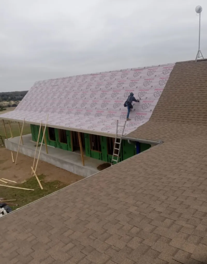 Worker preparing underlayment for a metal roof installation in Wenatchee